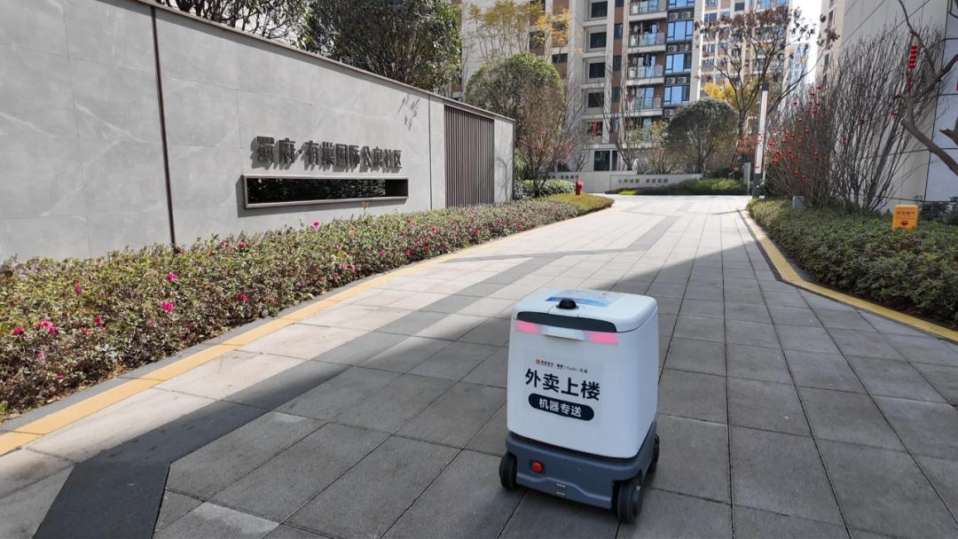 Contactless delivery robot arriving at a residential building entrance.